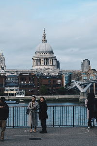 People walking by buildings against sky in city