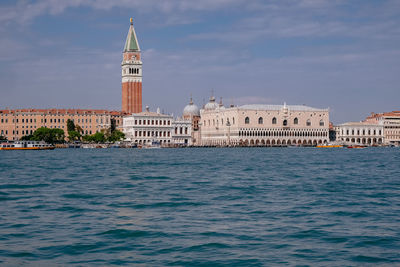 View of buildings by sea against sky in city