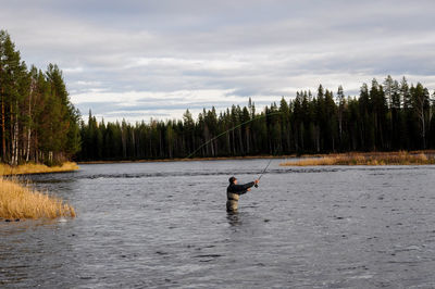 Man  fishing in the river against sky