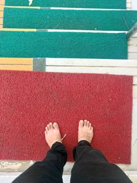 Low section of man standing on doormat over steps