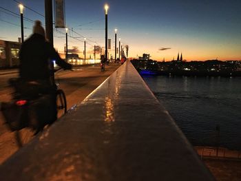 Silhouette person on suspension bridge against sky during sunset