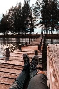 Low section of person relaxing on wooden footbridge 