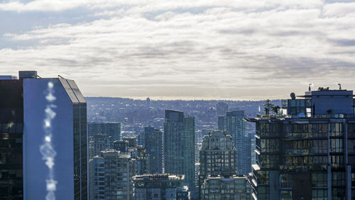 View of buildings in city against cloudy sky