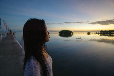 Woman looking at sea against sky during sunset