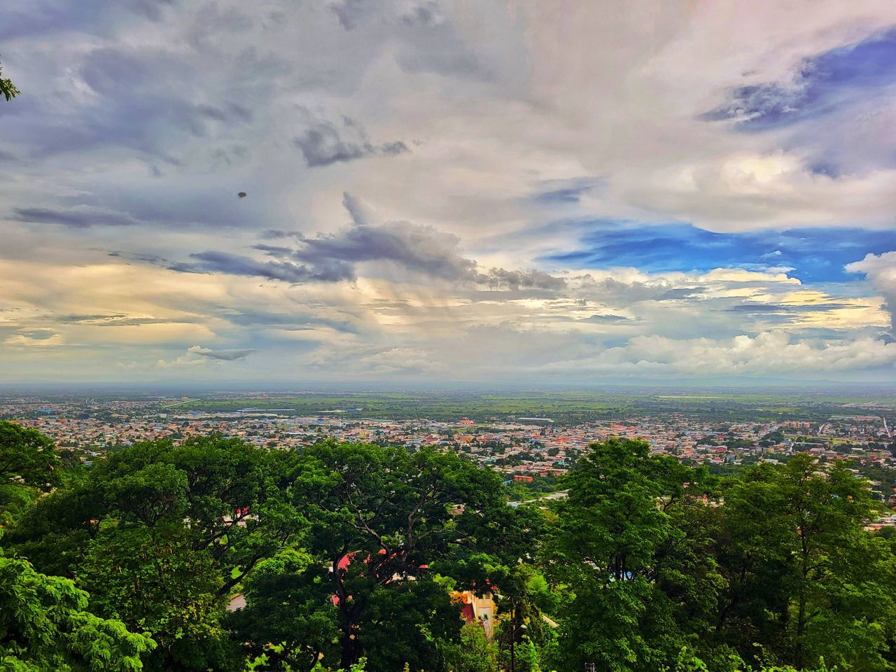 sky, nature, environment, cloud, horizon, landscape, city, architecture, plant, hill, beauty in nature, scenics - nature, tree, rural area, morning, land, building, cityscape, travel, building exterior, outdoors, plain, travel destinations, no people, sunlight, field, built structure, dramatic sky, urban skyline, tourism, natural environment, high angle view, social issues, residential district, tranquility, grass, summer, cloudscape, blue, aerial view, water, horizon over land, sea, forest, dusk, high up, day, town, flower, green, multi colored, sun, freshness