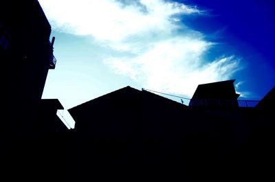 Low angle view of silhouette building against blue sky