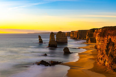 Rocks on beach against sky during sunset