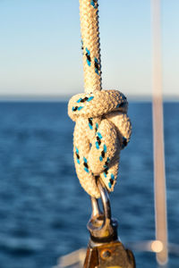 Close-up of rope tied on bollard against sea