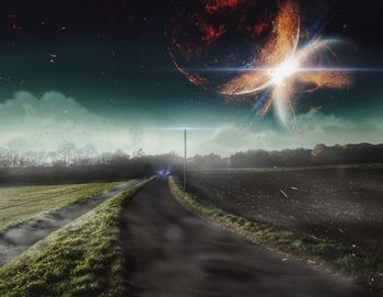 Road amidst field against sky at night