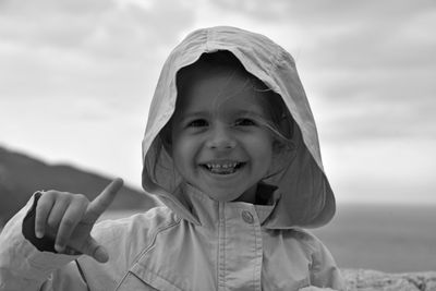 Portrait of smiling girl wearing hooded jacket against sky