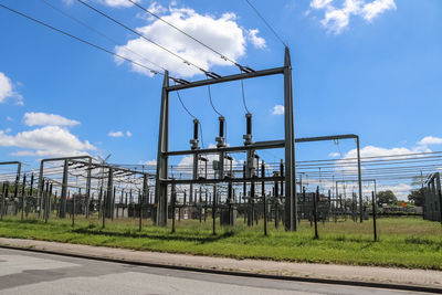 Electricity pylon by road against sky