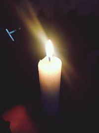 Close-up of illuminated candle in darkroom