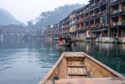 Wooden boat in lake against buildings