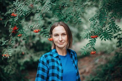 Portrait of beautiful young woman standing against plants