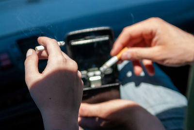 Midsection of man holding smart phone while car