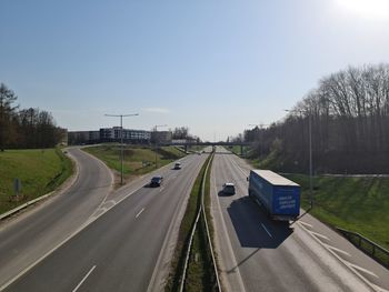 Vehicles on road against sky in city