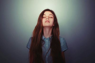 Portrait of young woman standing against gray background