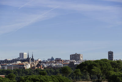 Trees and buildings against blue sky