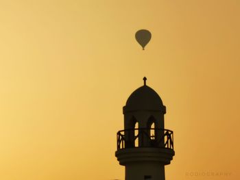 Low angle view of silhouette tower against orange sky