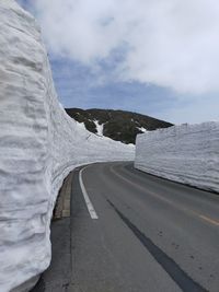 Road amidst snowcapped mountains against sky