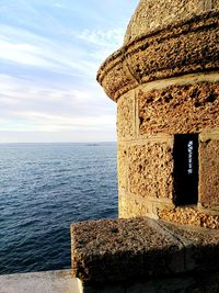 Stone wall by sea against sky