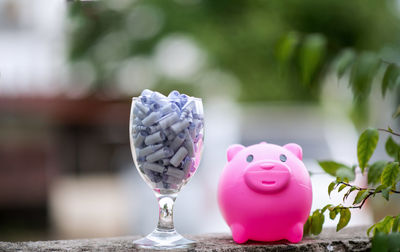 Close-up of piggy bank and wineglass on table