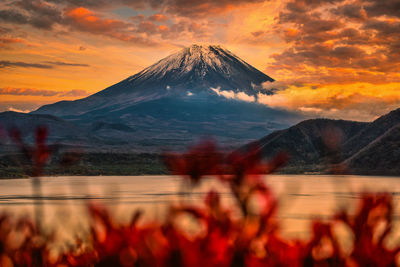 Group of people on snowcapped mountain against orange sky