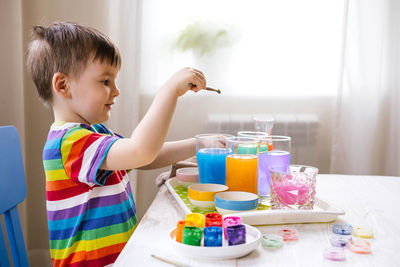 Smiling boy playing with watercolor at home