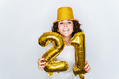 Portrait smiling woman wearing hat holding balloons against white backgrounds