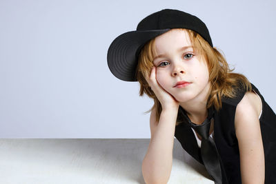 Portrait of girl wearing hat against wall