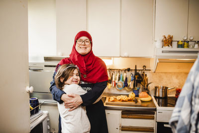 Portrait of happy mother with daughter standing at home