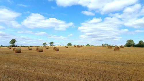 Hay bales on field against sky