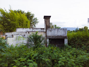 Abandoned bridge amidst trees on field against sky