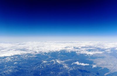 Aerial view of snowcapped mountains against blue sky