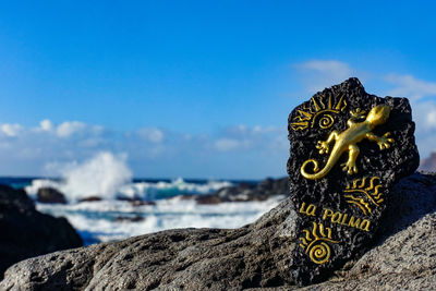 Close-up of statue by rock against sea