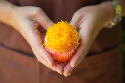 A  mamon cake with golden thread topping in woman hand 