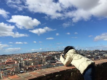 Woman standing at building terrace against cloudy blue sky in city