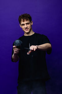 Side view of man with arms raised standing against blue background