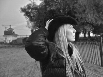 Profile view of thoughtful mature woman wearing hat while standing on field