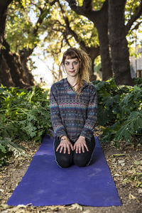 Portrait of woman kneeling on exercise mat at park