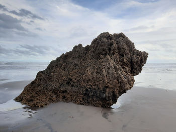 Rock formation on beach against sky