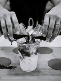 Close-up of hand holding drink on table