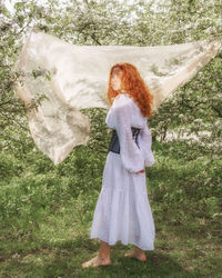 Woman standing by tree on field