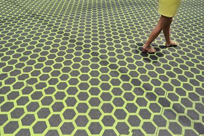 Low section of woman walking on patterned pavement