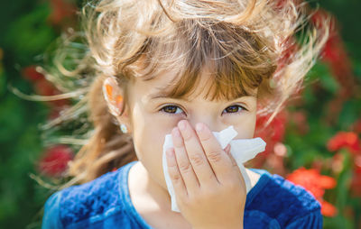 Portrait of sick girl having allergy wiping nose