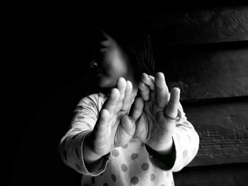 Girl looking away and showing stop gesture while standing against wall at home