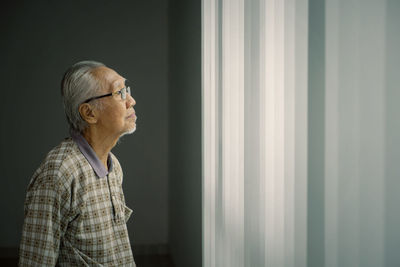 Side view of man looking through window