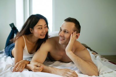 Portrait of young couple lying on bed at home