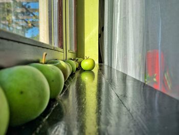Close-up of granny smith apples arranged on table by window