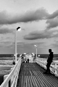 Men standing on pier over sea against sky